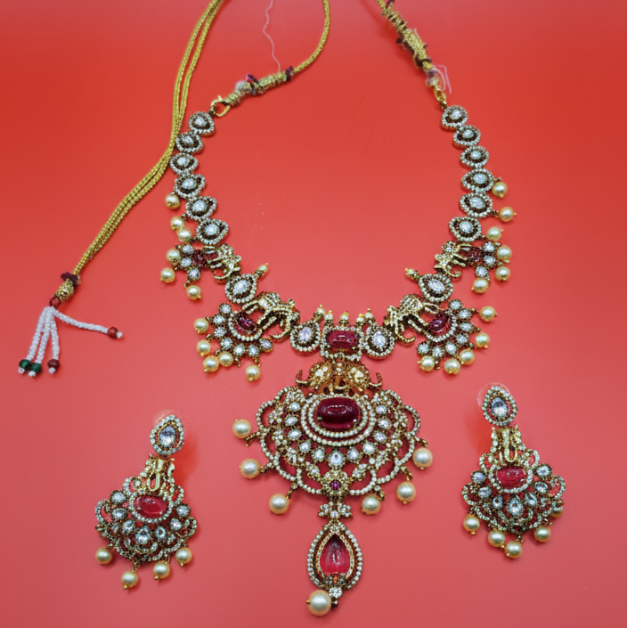 Ornate gold necklace with red stones on a red background